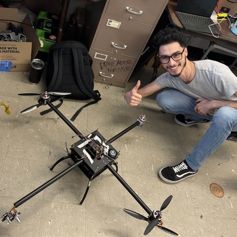 Parsa Rezaei beside the heavy-lift carrier quadcopter, showing its carbon arms, GPS module and flight controller