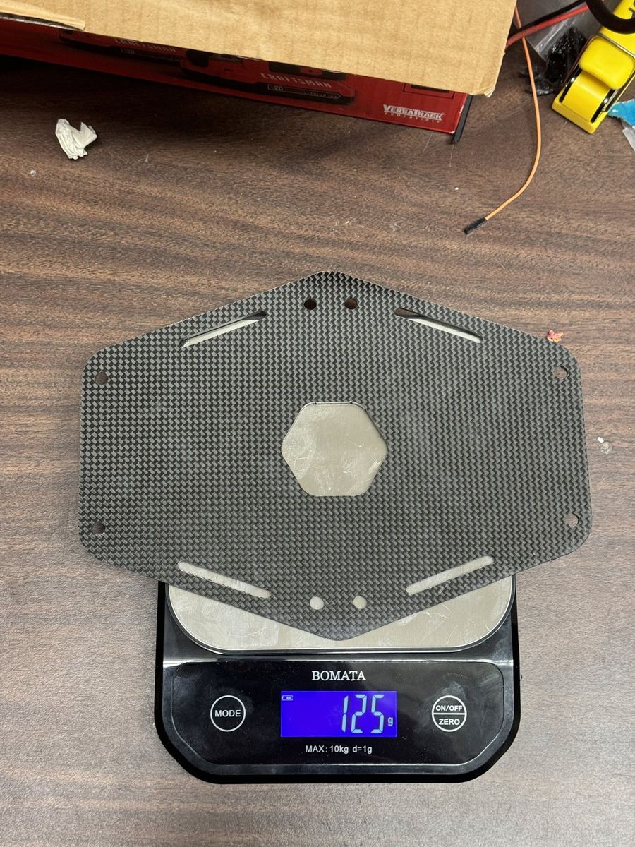 Carbon-fiber base plate on the scale; mass is the whole argument