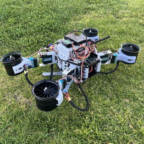 The morphing multirotor on grass, thruster pods and wiring mounted on servo-driven rails