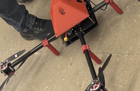 Carbon-fibre quadcopter with a 3D-printed canopy on the laboratory floor